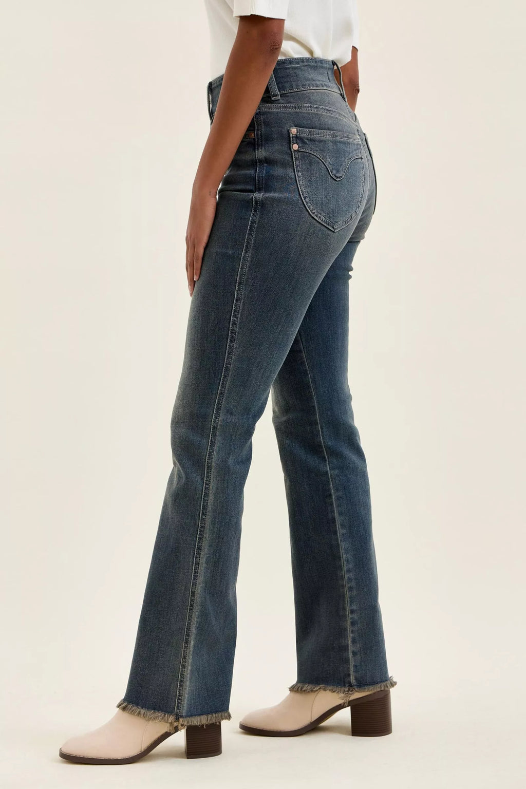 High-waist dark denim jeans with curved back pockets and frayed hem at the ankle.