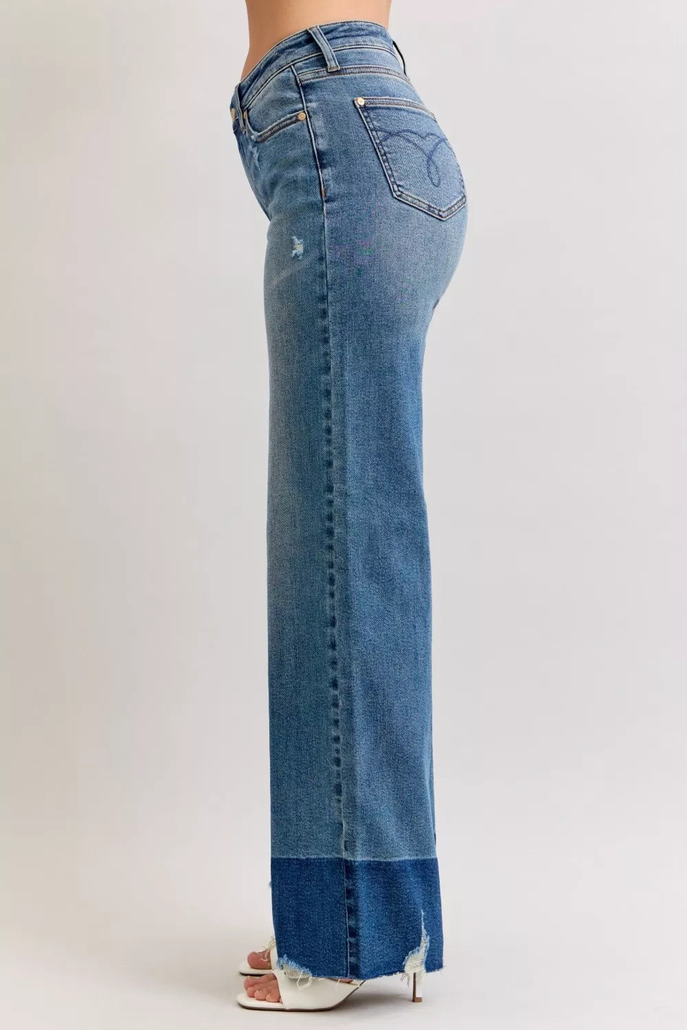 Side view of high-waist straight jeans in dark denim with raw frayed hem and back pocket