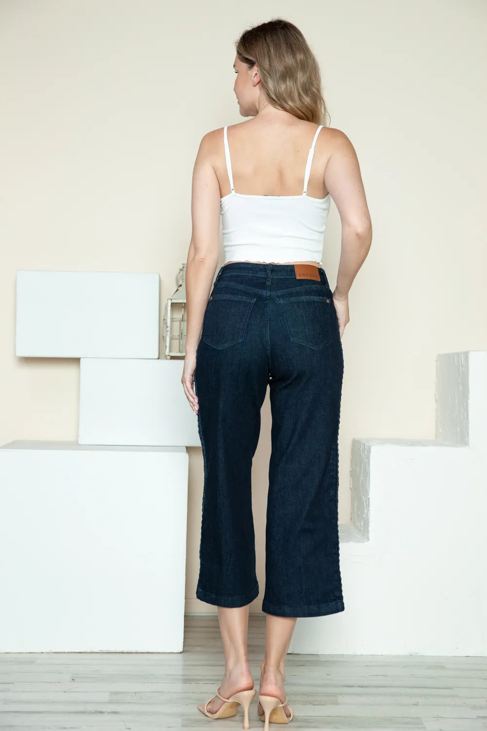 Dark denim crop wide-leg jeans back view with braided side seam detail