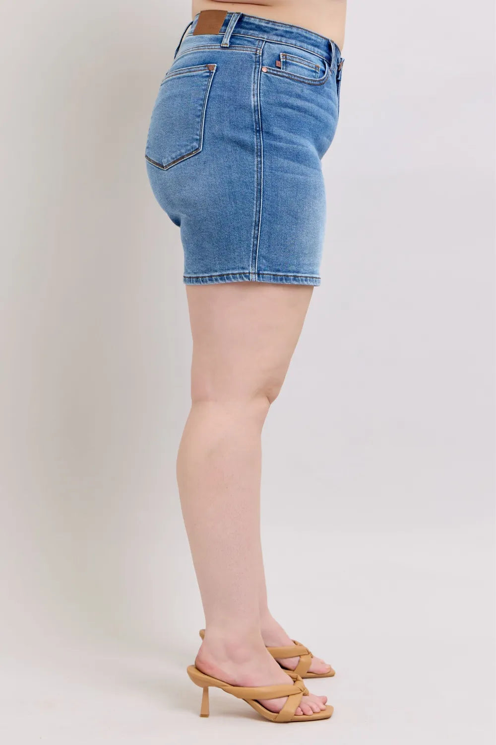Medium wash denim shorts, side view, with front pockets and belt loops