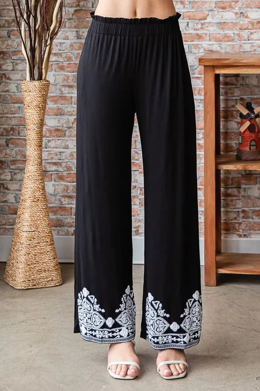 Black wide-leg pants showing elastic waistband and white patterned border at hem