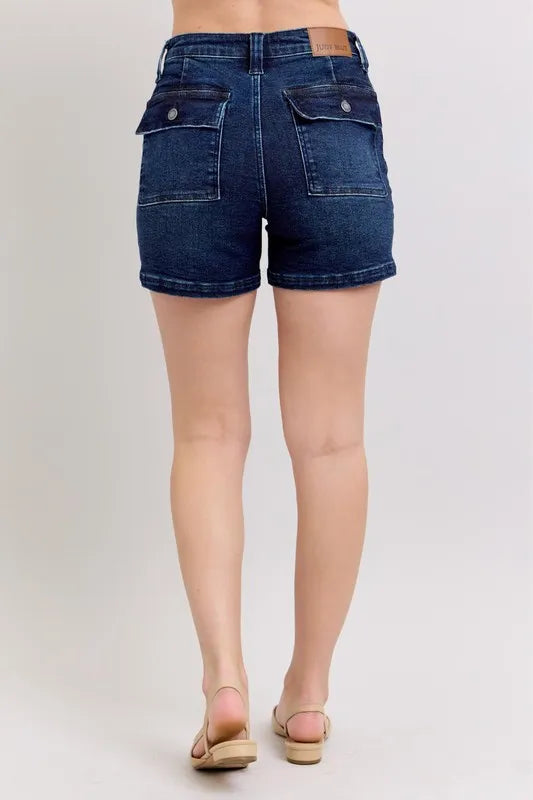 Back view: high-waist dark denim shorts with two flap pockets and belt loops