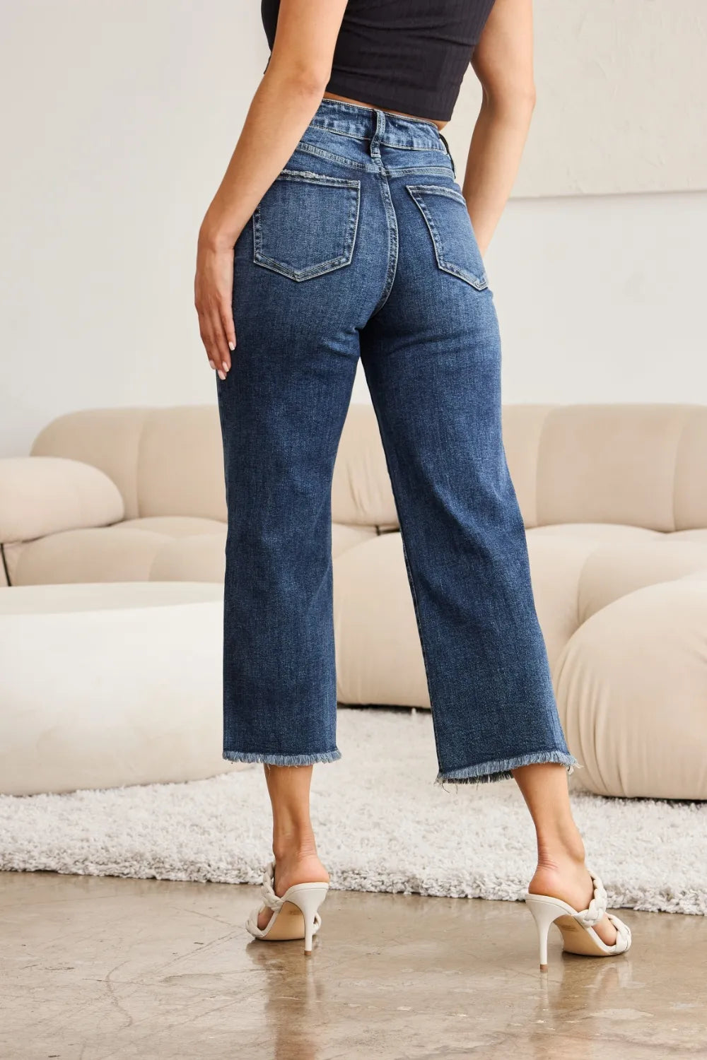 High-waist dark-wash jeans back view with yoke seams and raw cuff hem