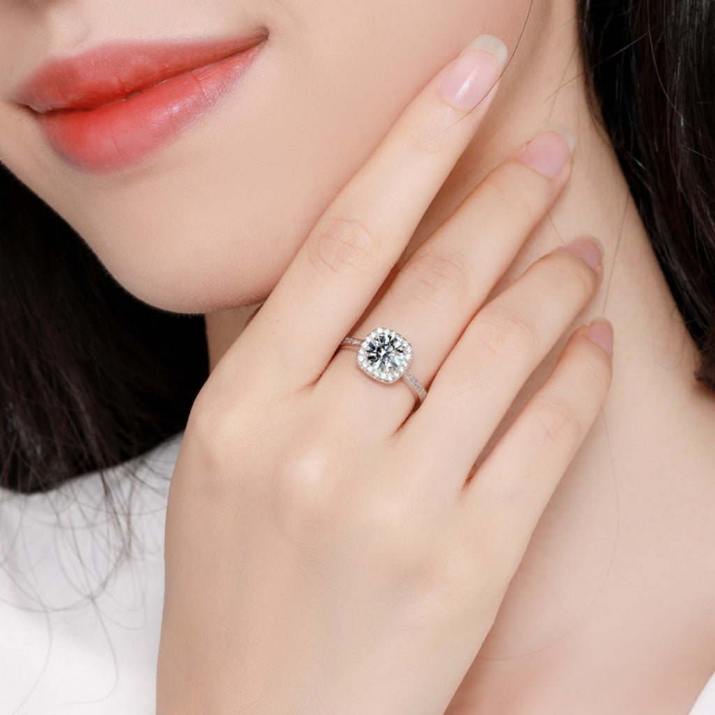 Moissanite halo ring on finger, sterling silver band with pavé detailing