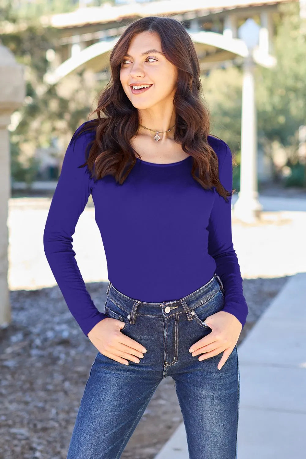 Blue long-sleeve round-neck bodysuit worn under a denim waistband