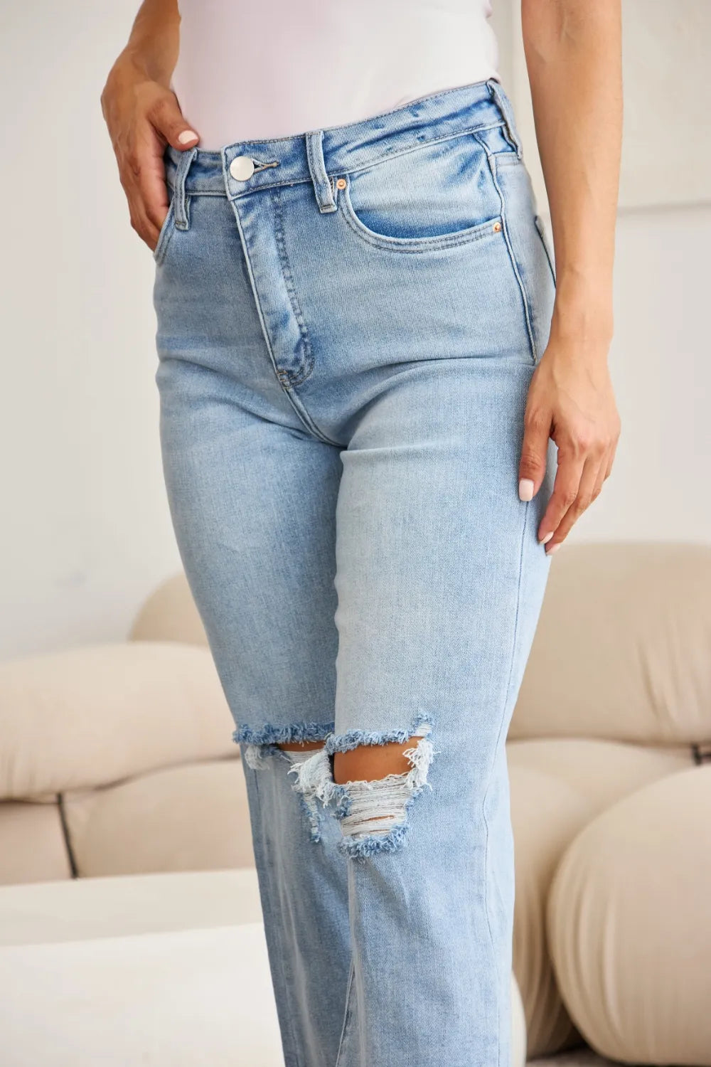 Light wash high-waist denim with knee rips and frayed raw hem