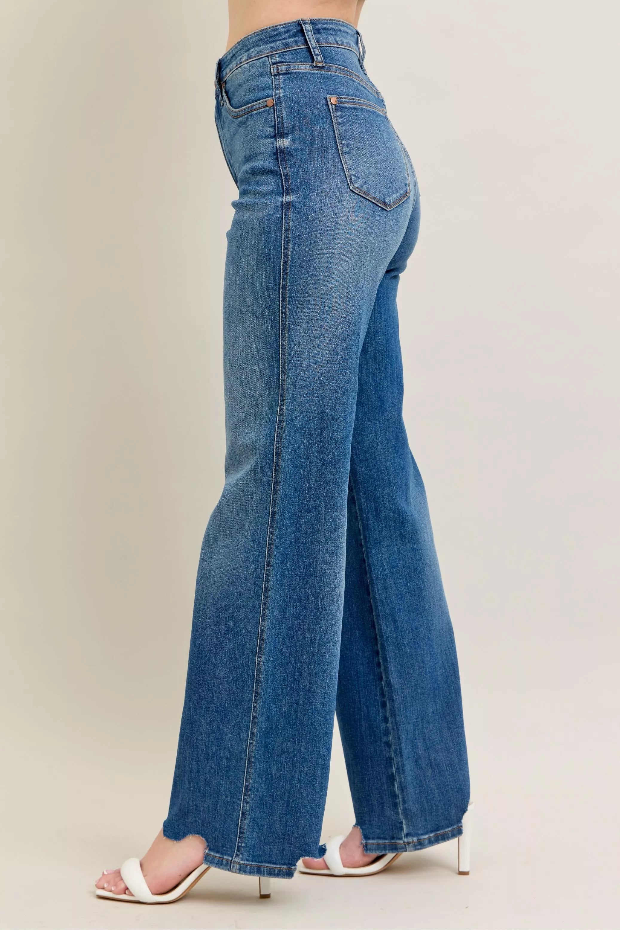 Back view of medium-wash wide-leg jeans with raw frayed cuffs