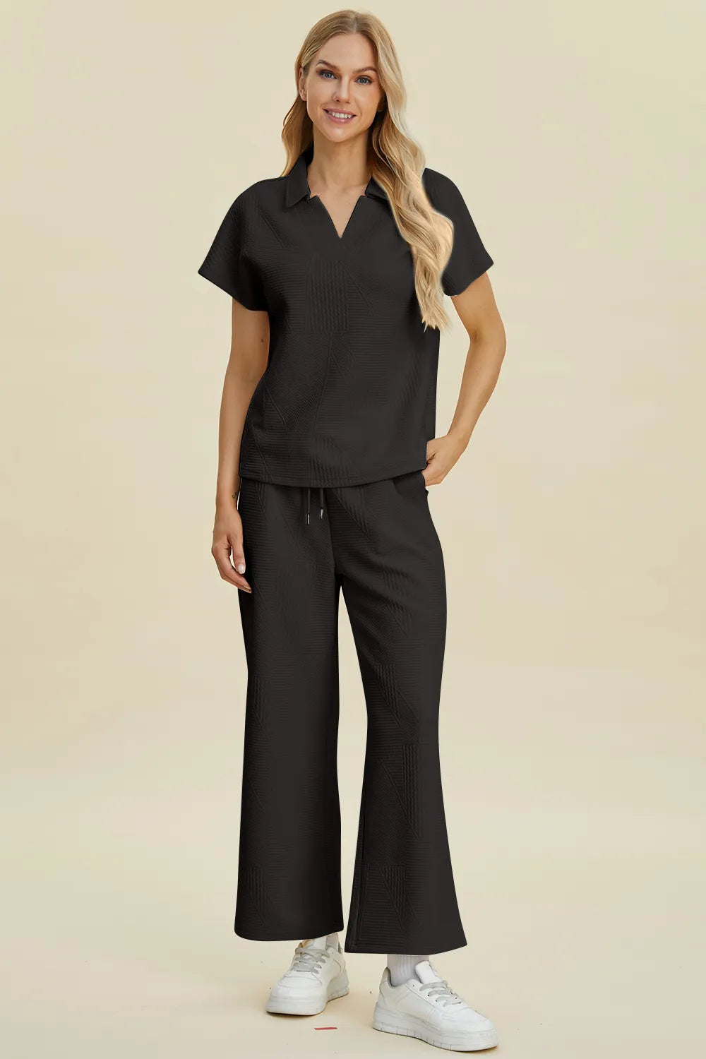 Schwarzes Zweiteiler-Set aus Polohemd und Hose mit Kordelzug, frontale Ganzansicht