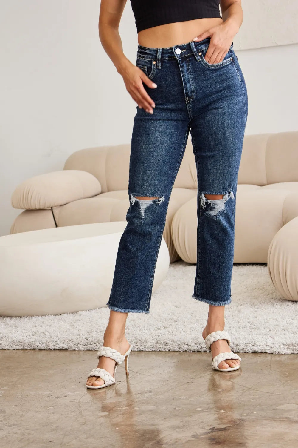 High-waist denim jeans, dark wash, raw hem with knee distress and frayed tears
