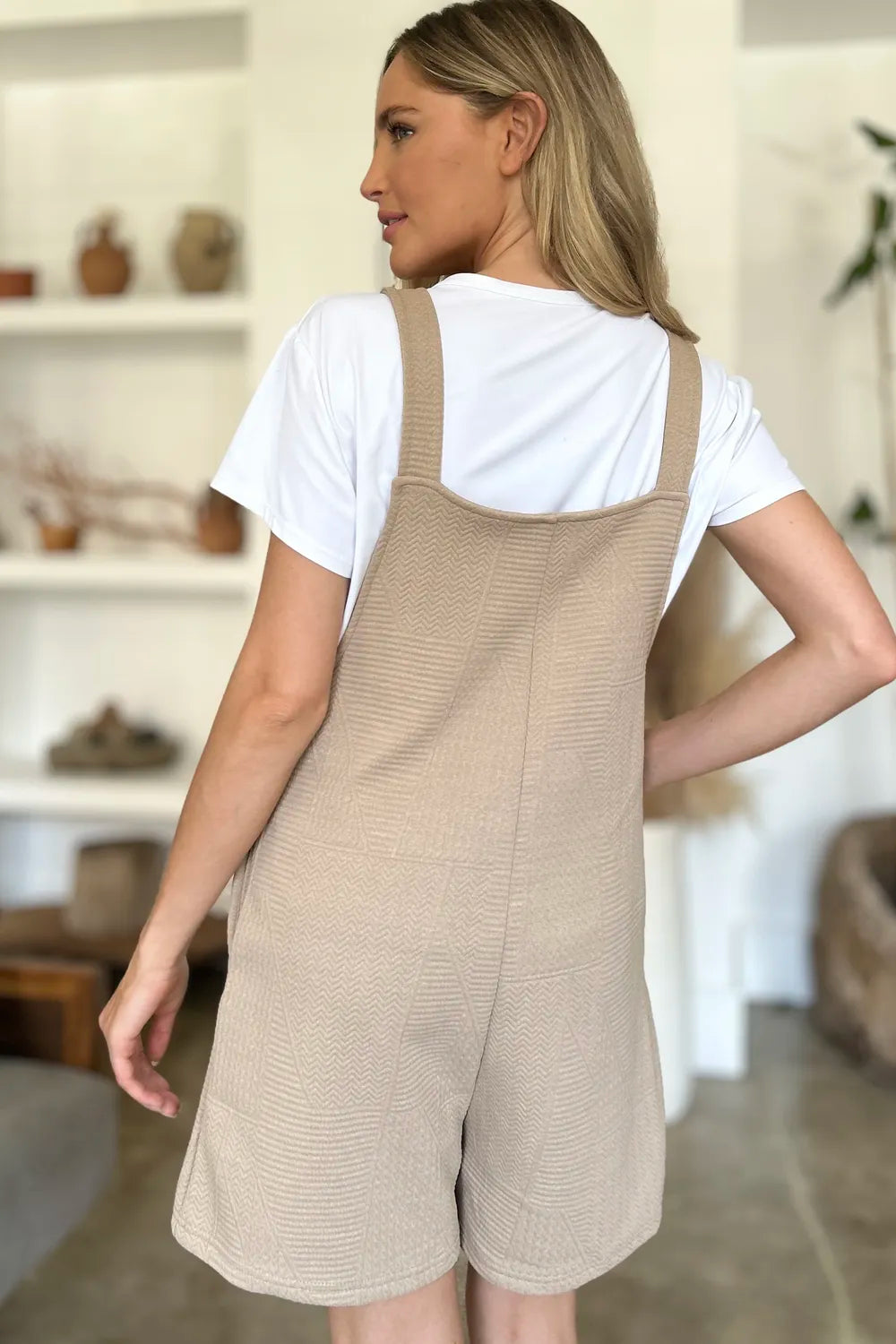 Khaki textured sleeveless romper from back view with wide straps and short legs