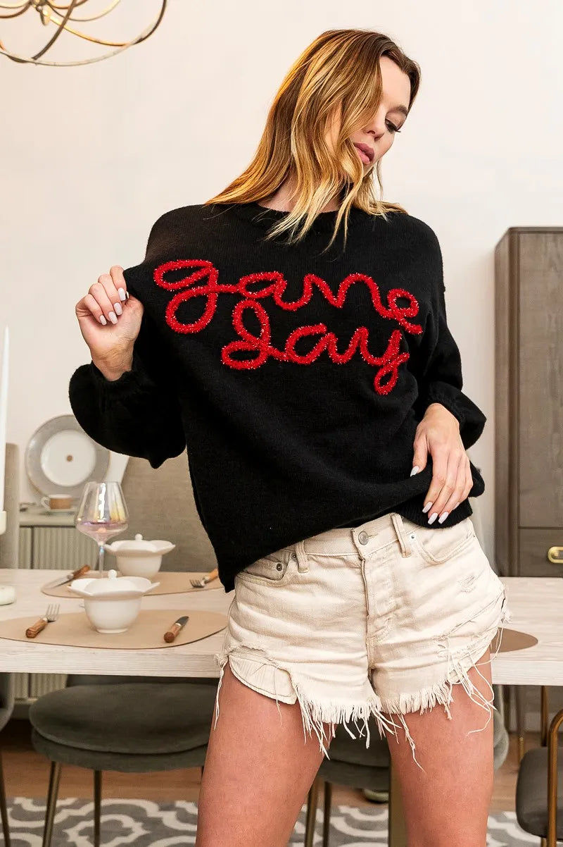 Black pullover sweater with red “Game Day” knit lettering and crew neck