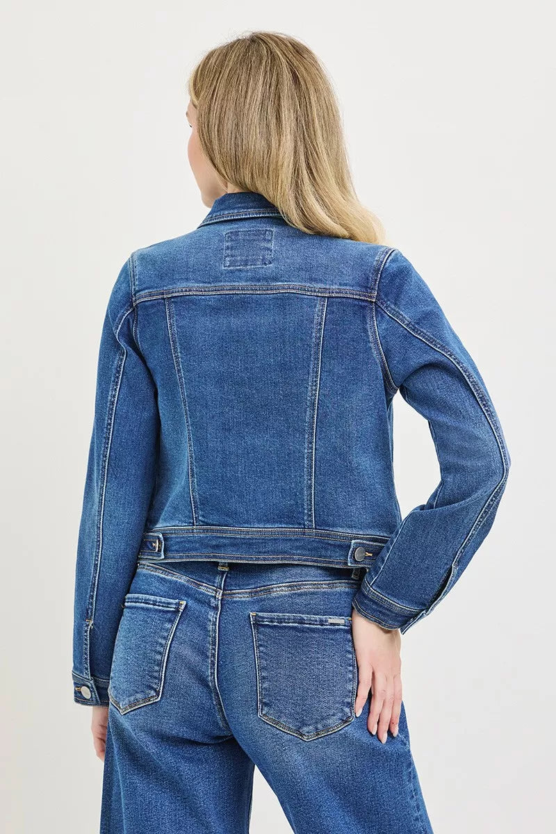 Back view: medium-wash fitted denim jacket with yoke seams and flap pockets