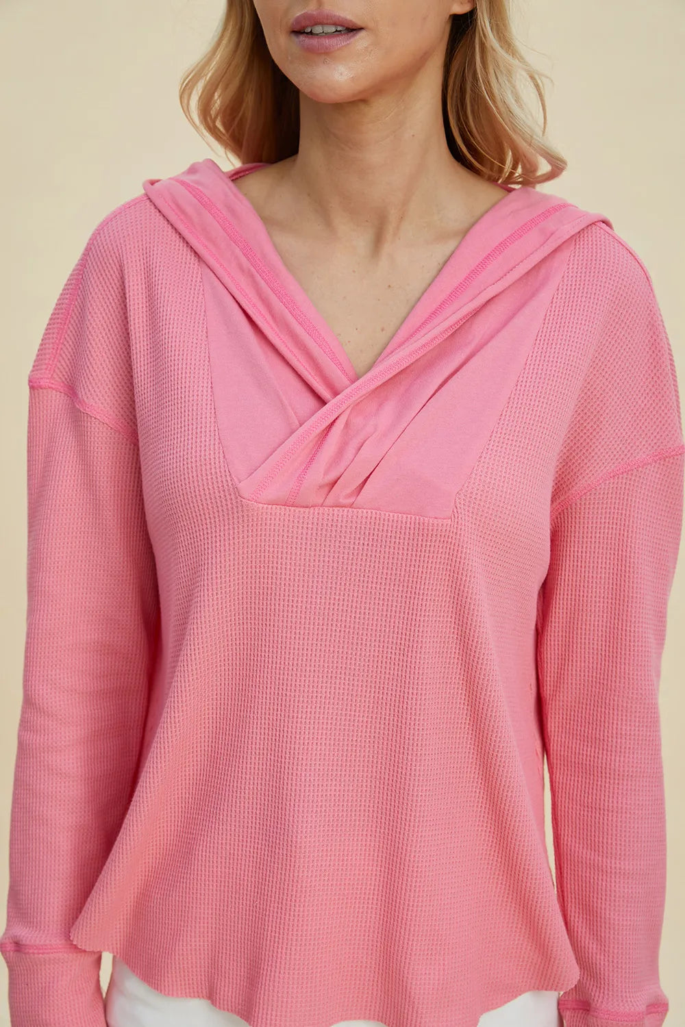 Pink hoodie close-up: cowl-style crisscross neckline with hood and long sleeves