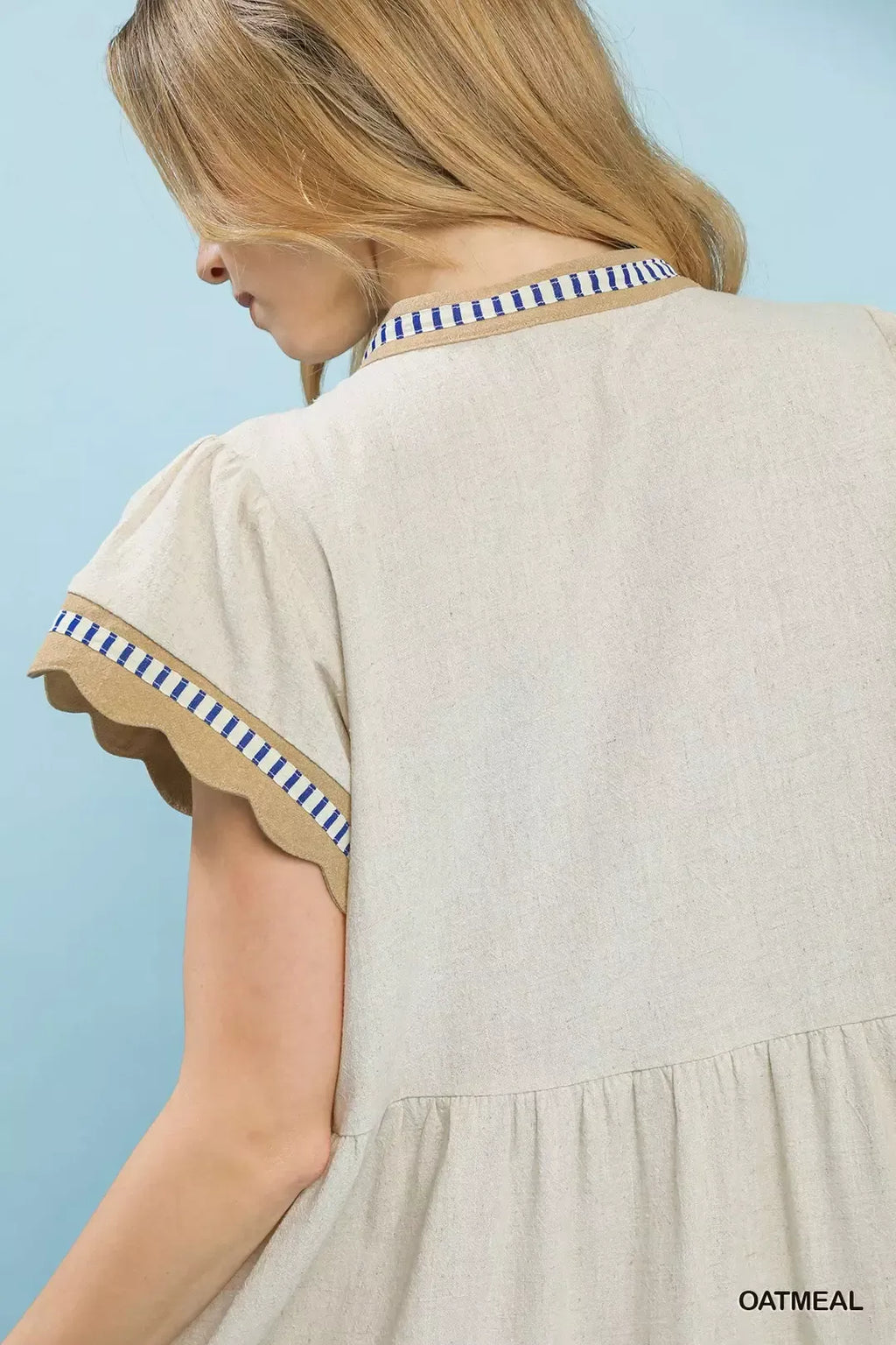 Close-up of oatmeal linen dress with blue striped collar and neckline trim