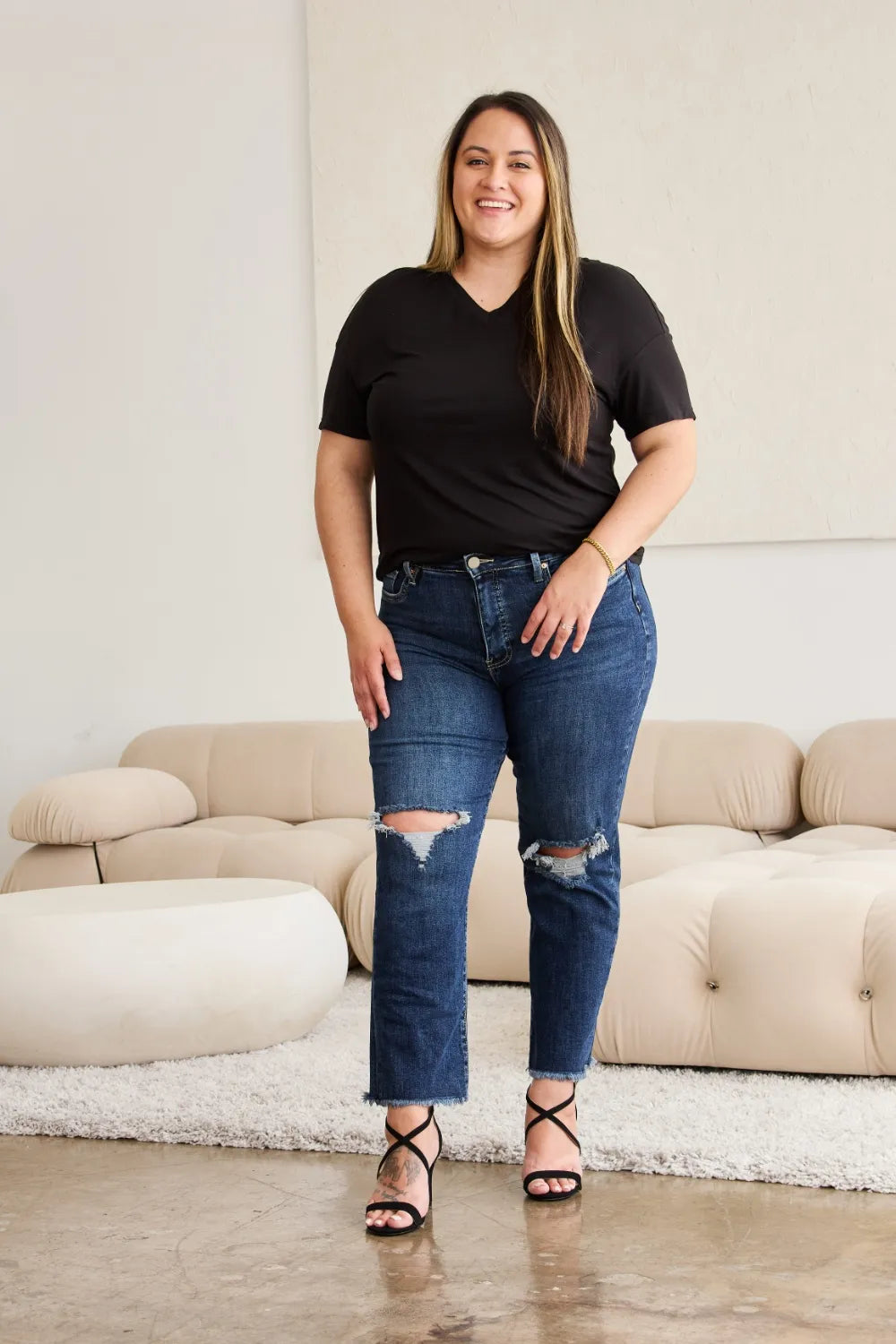 High-waist dark wash jeans with raw hems and distressed knee rips