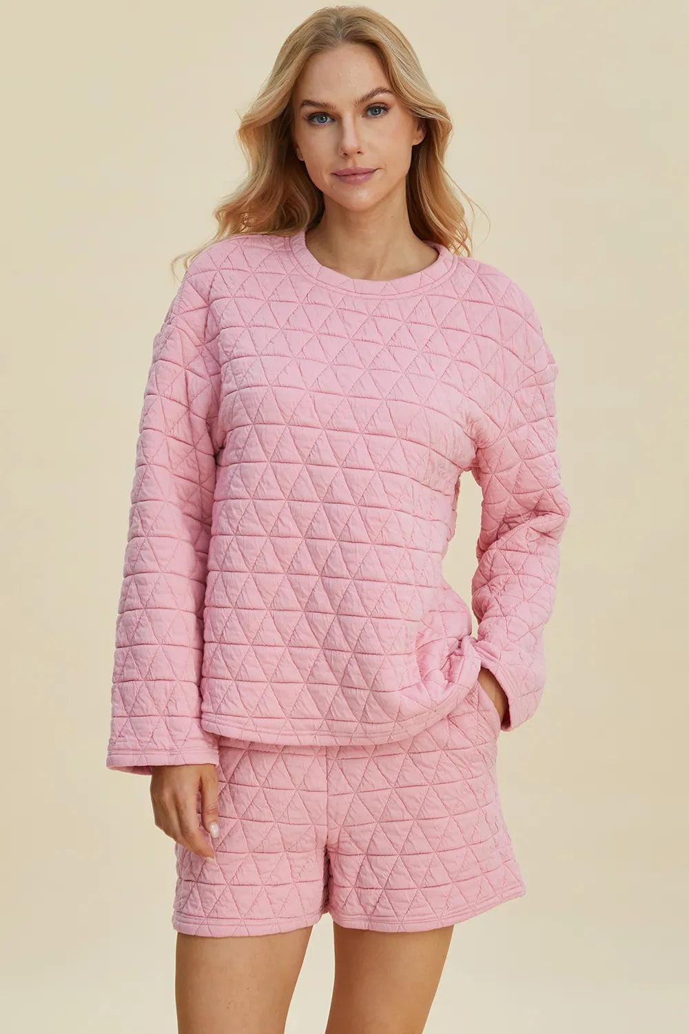 Pink quilted long-sleeve top and matching shorts set, round neck, geometric texture.