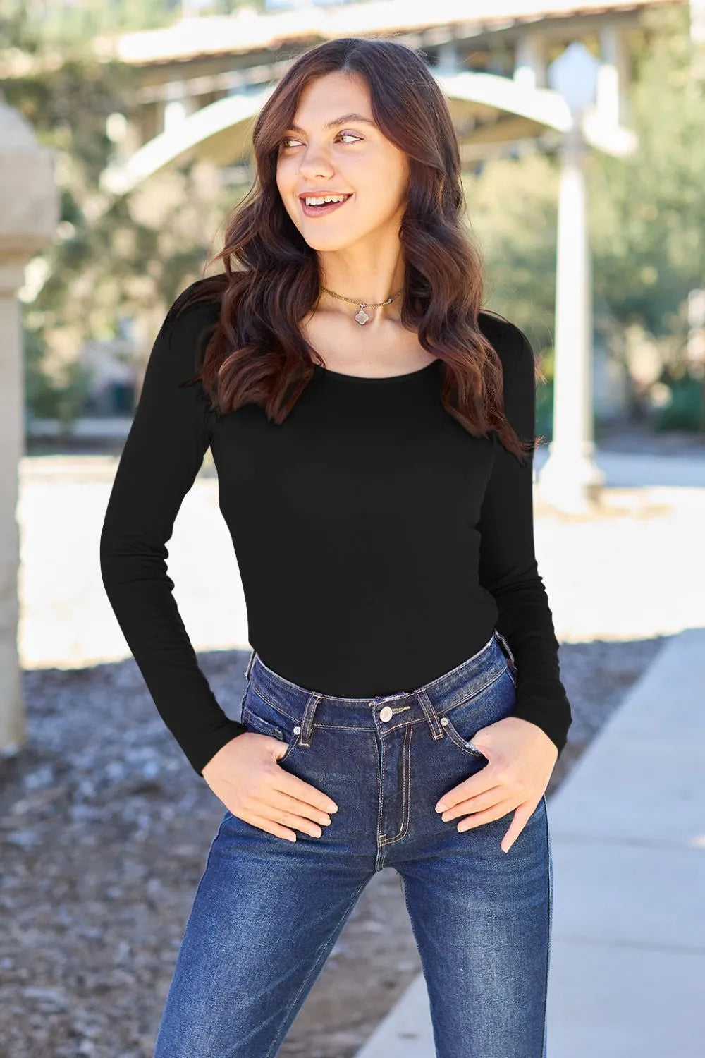 Black long-sleeve round-neck bodysuit, fitted silhouette and smooth fabric.