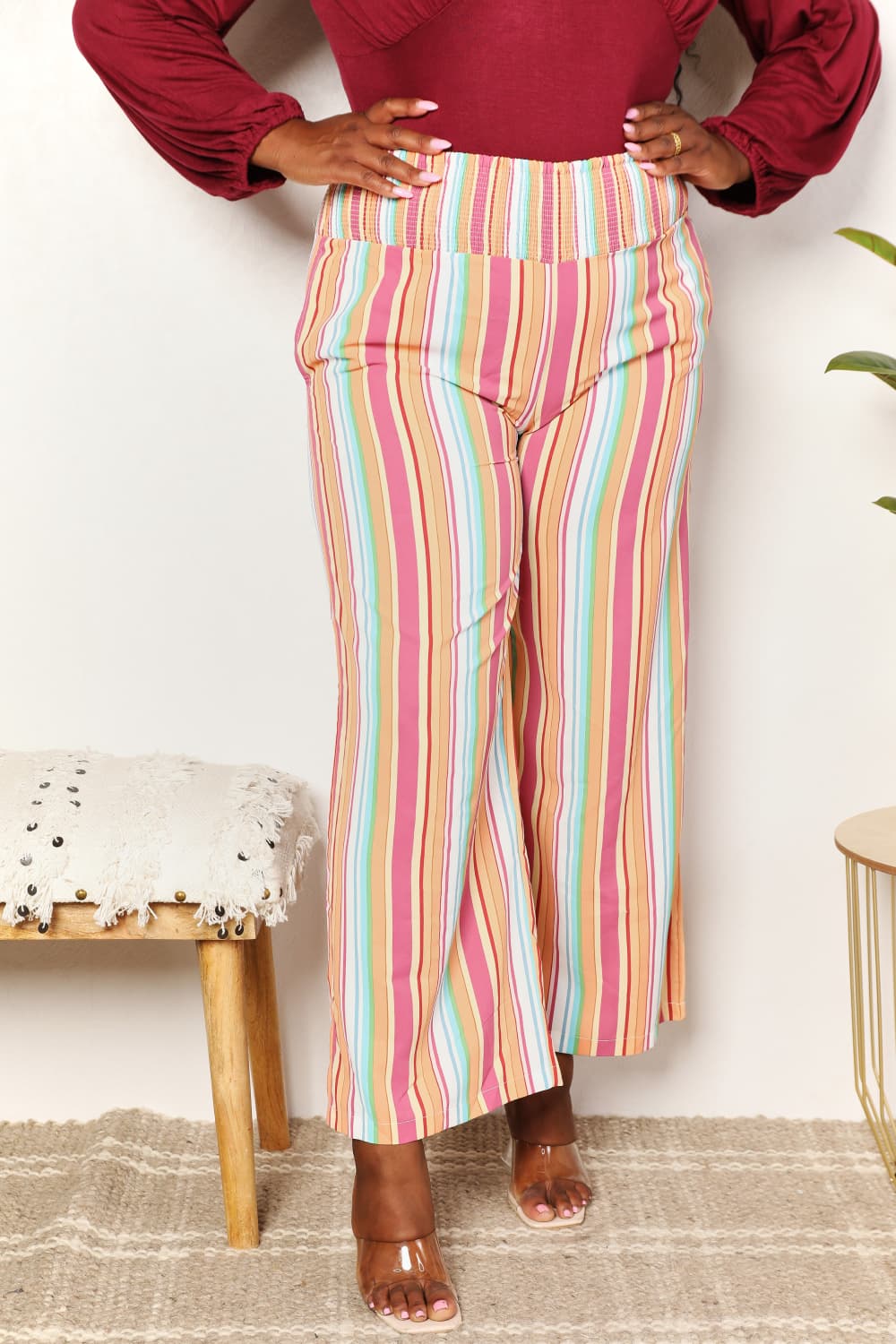 Front view of striped smocked-waist pants with pockets and wide flare leg