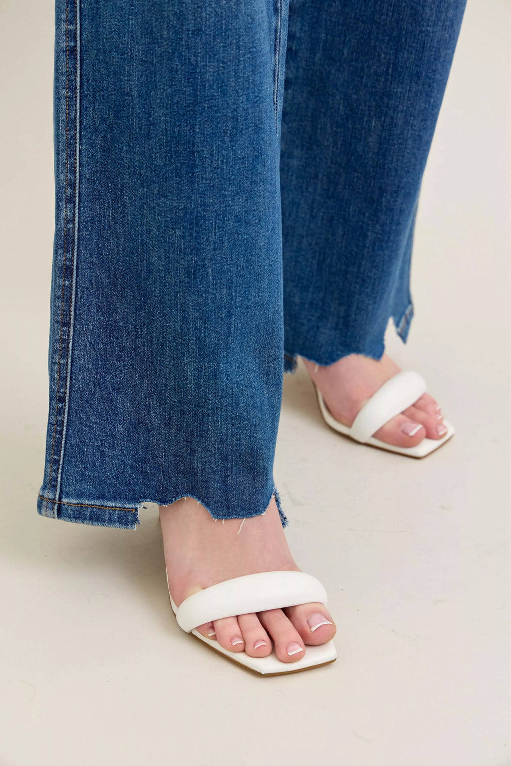 Medium-wash wide-leg jeans with chewed, frayed hem at the ankle