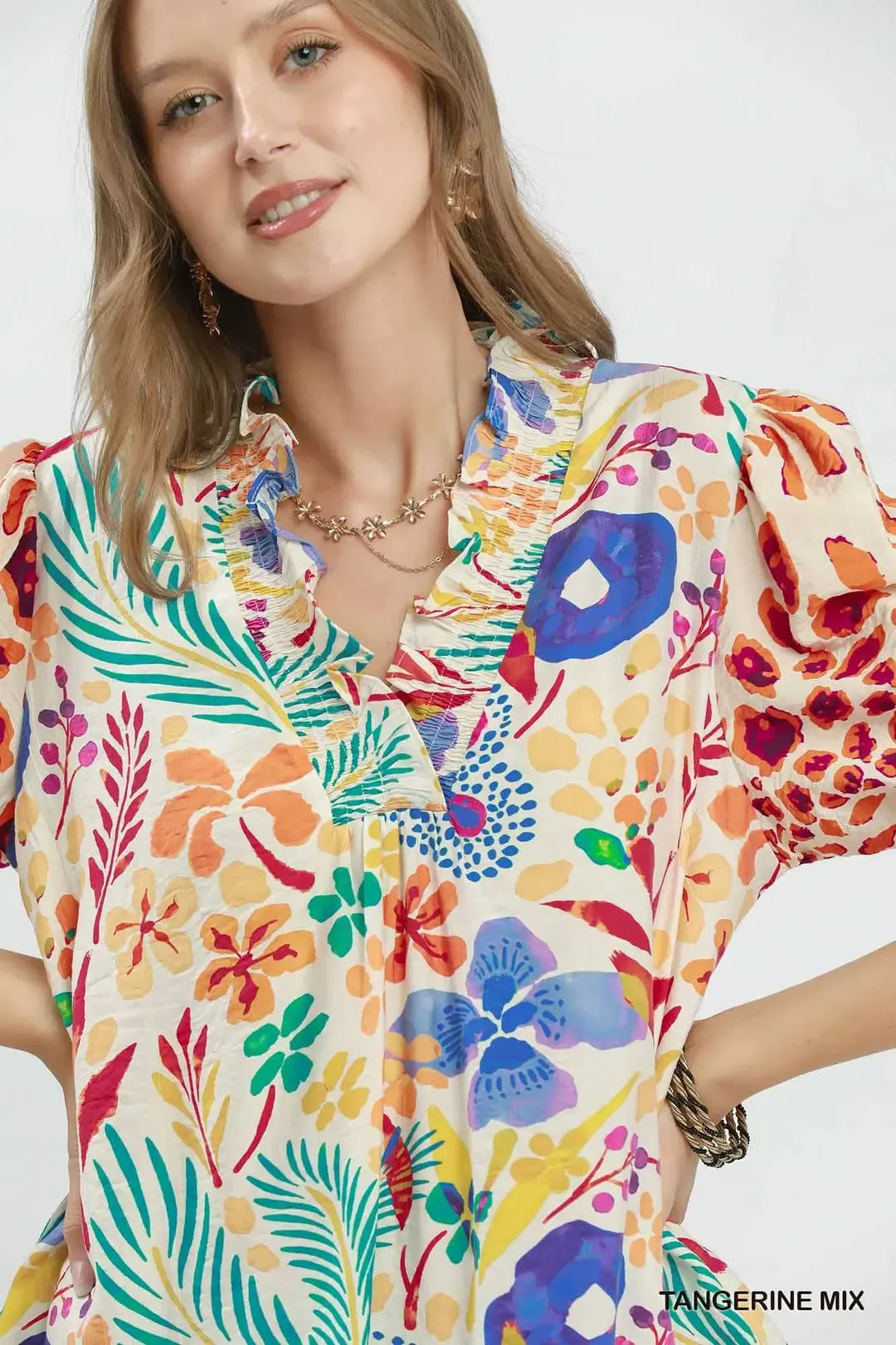 Close-up of V-neck ruffle trim and puff sleeves on multicolor printed top