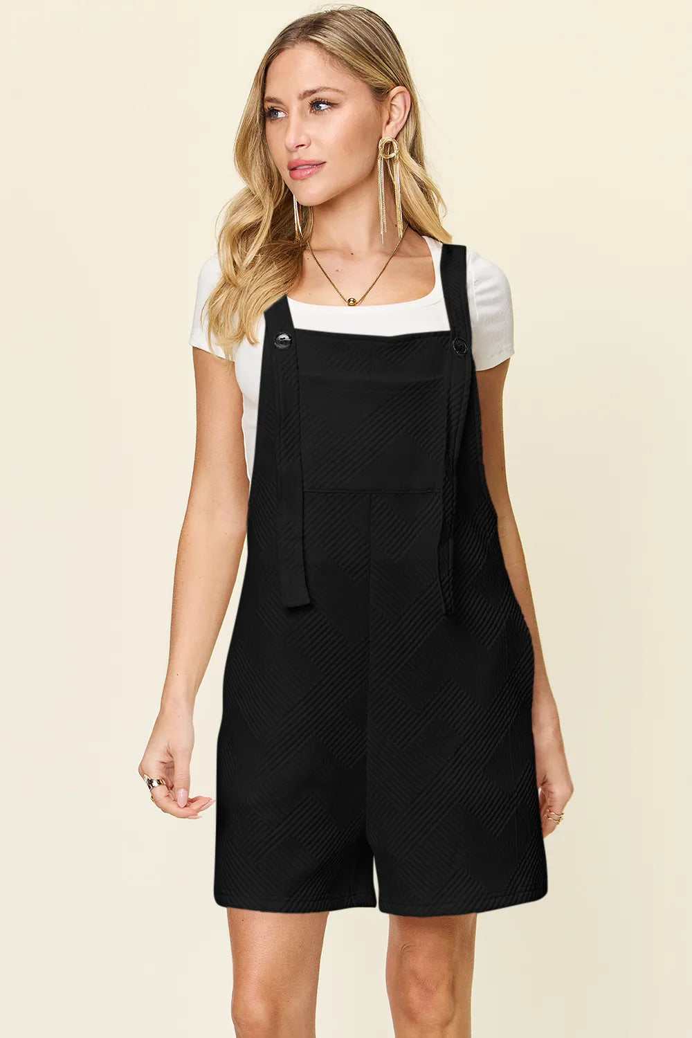 Black textured sleeveless romper with overall bib front and button straps