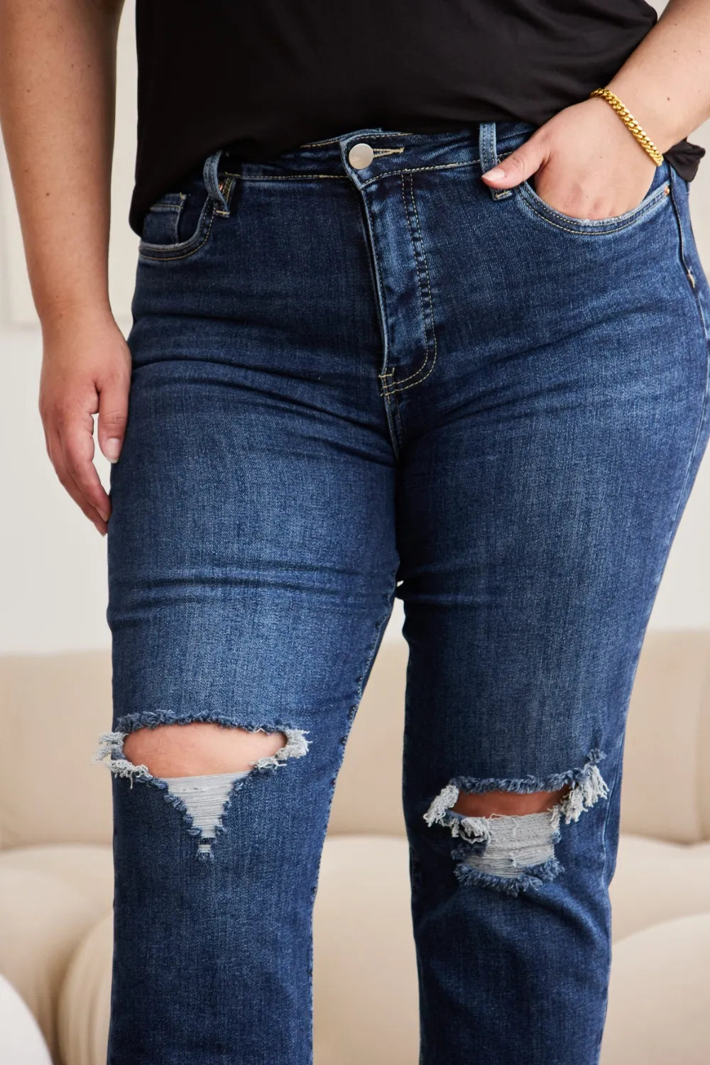 Close-up: dunkelblaue High-Waist Jeans mit Taschennaht und ausgefransten Knie-Rissen