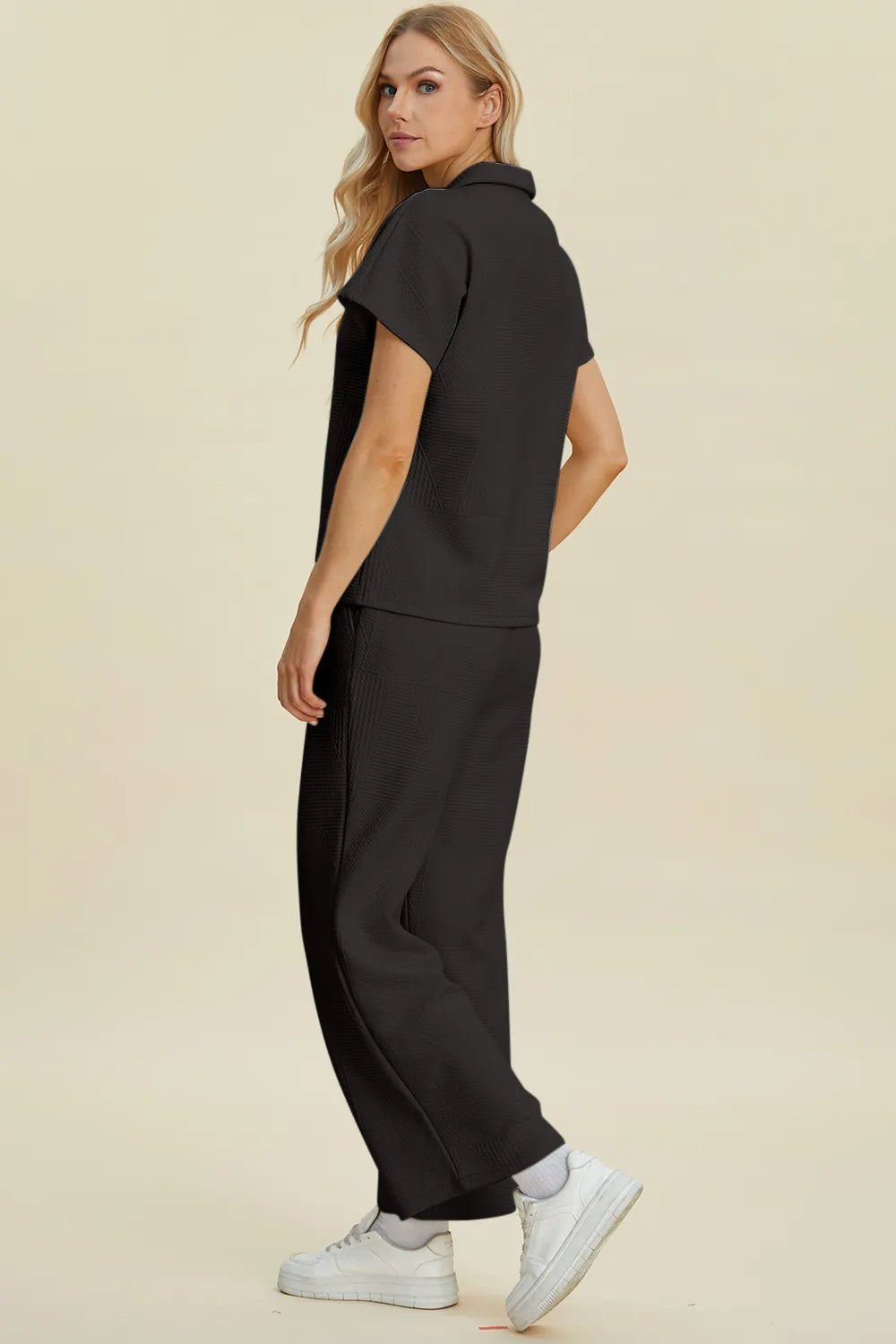 Black short-sleeve top with collar and wide-leg pants, side view