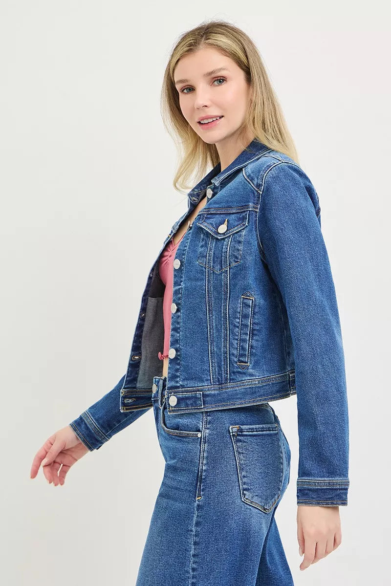 Side view: medium-wash fitted denim jacket with flap pockets and button front