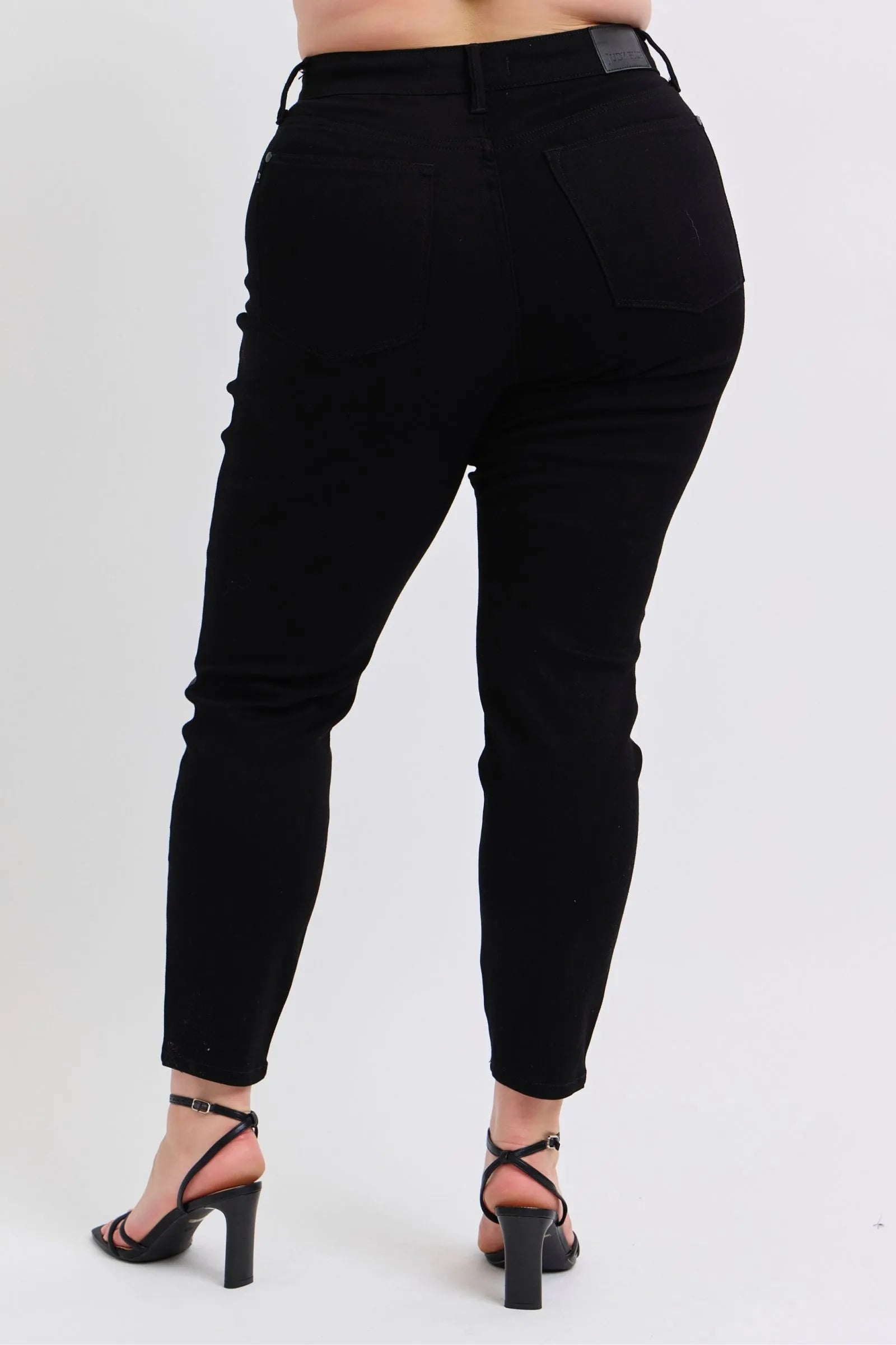 Black faux leather skinny pants, back view, slim ankle length and tapered fit