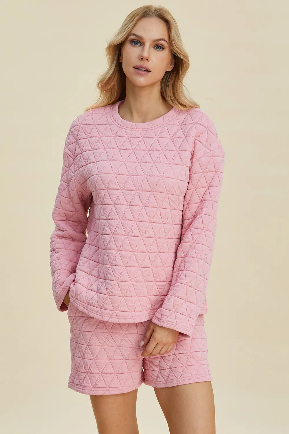 Pink textured long-sleeve top and matching shorts set with round neck and quilted pattern.