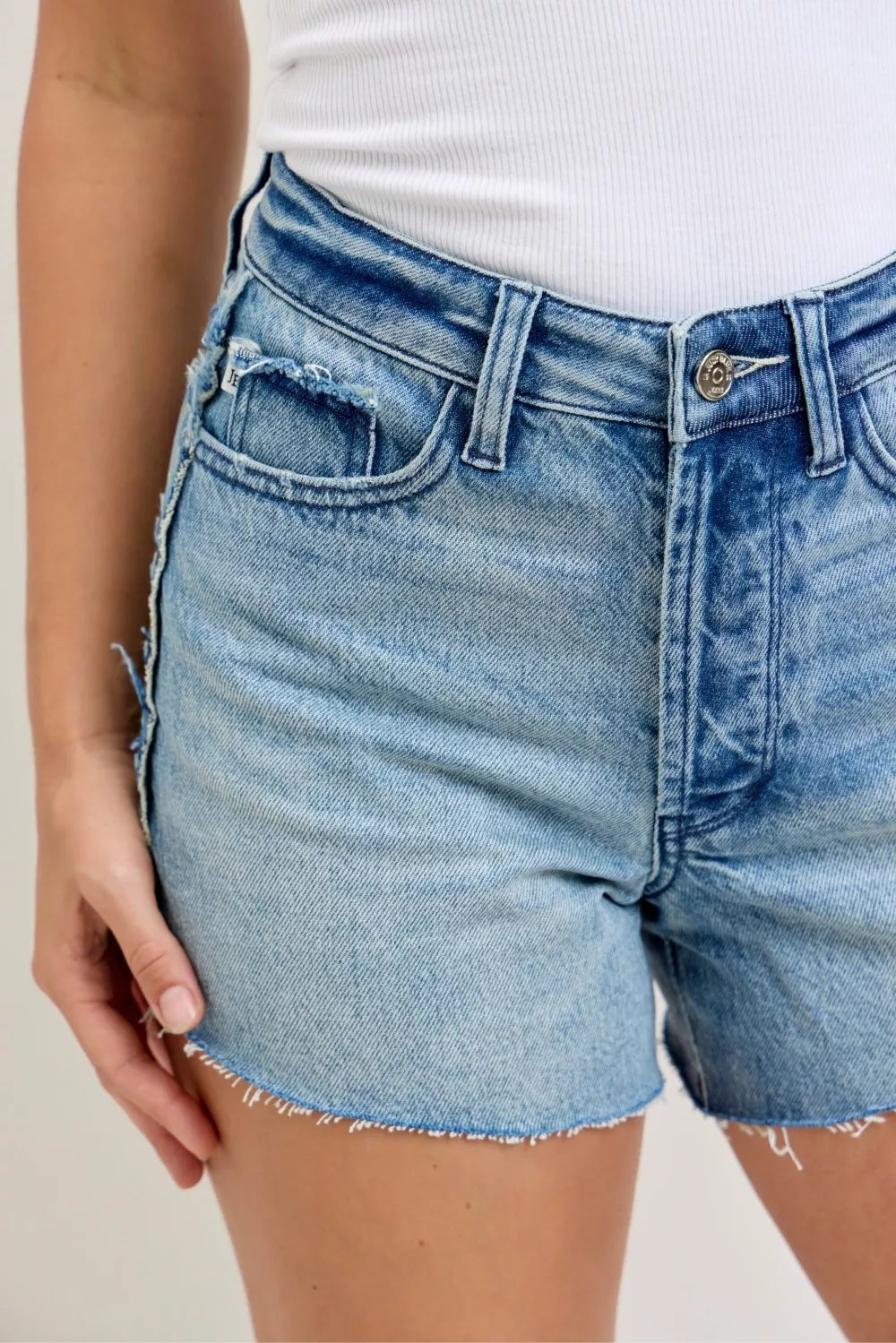 Denim cut-off shorts front pocket detail with stitched seams and frayed hem