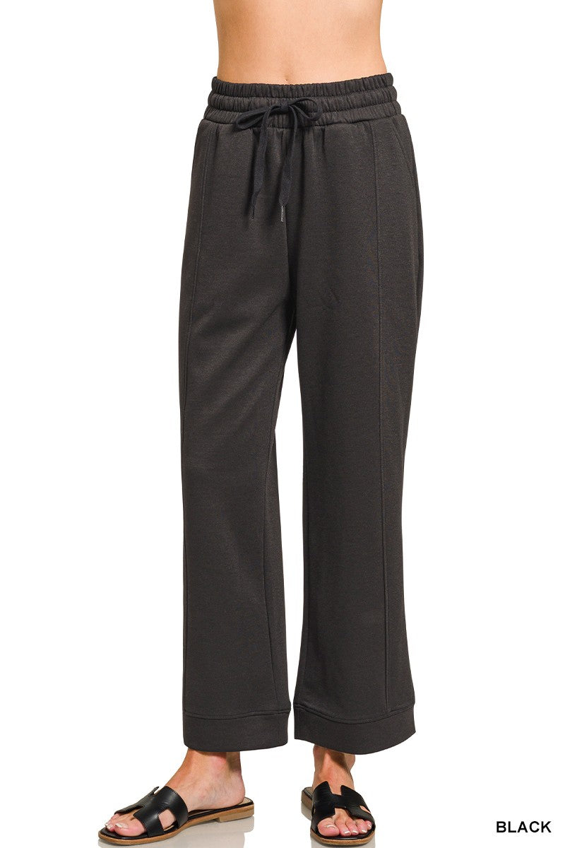 Black drawstring pants close-up: elastic waistband with tie cords, wide legs