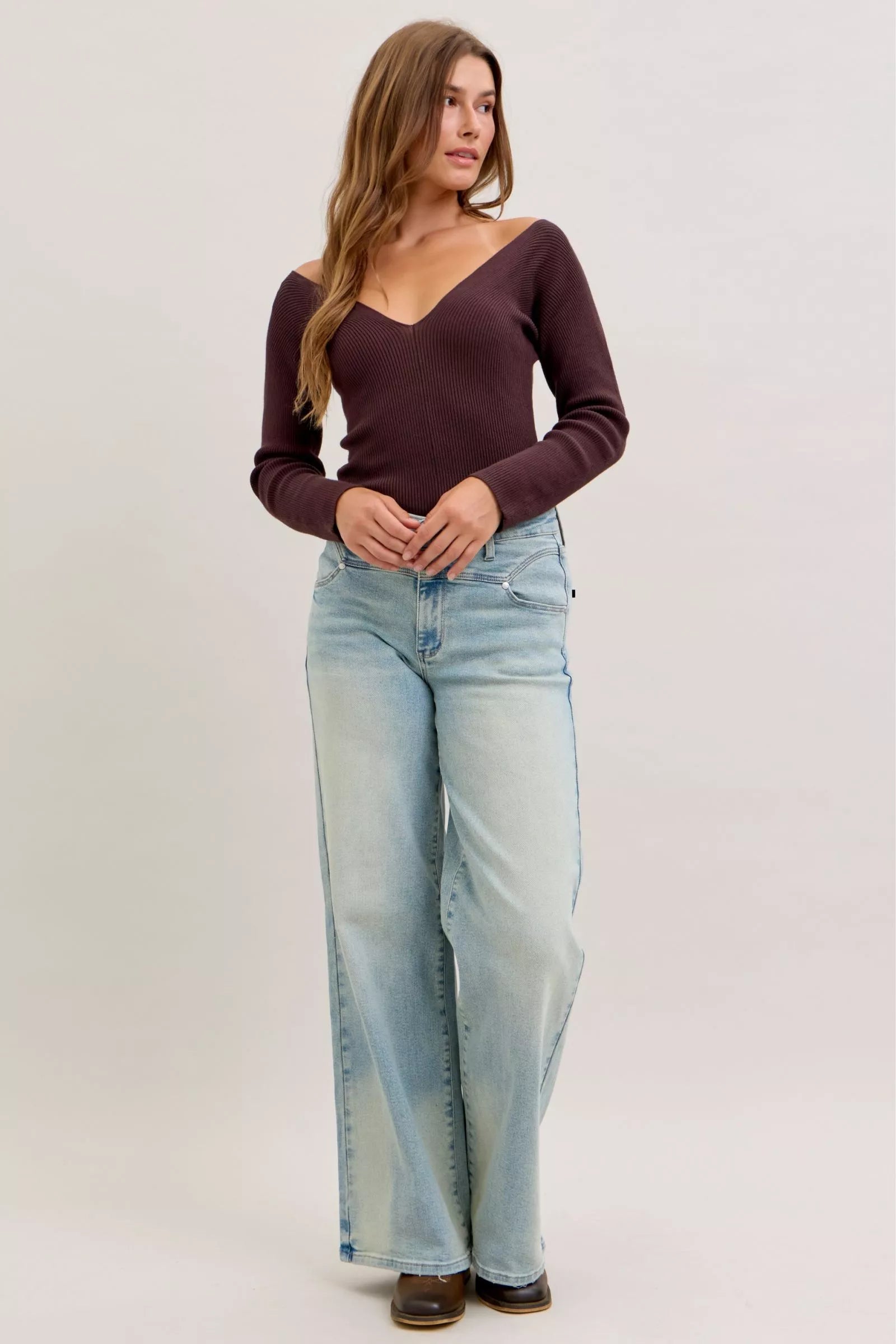 Light blue high-waist straight jeans on model, front view with whisker wash and rolled hem