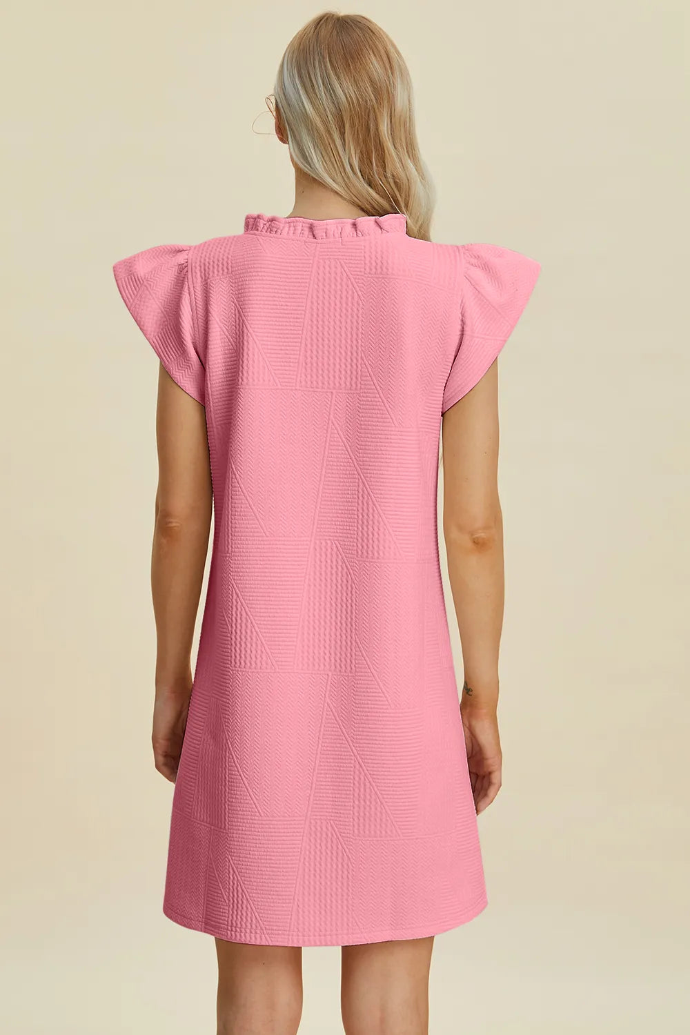 Pink cap-sleeve dress with ruffled shoulders at back and textured geometric pattern