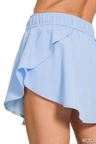 Light blue woven skort with asymmetrical ruffle panels at the hem