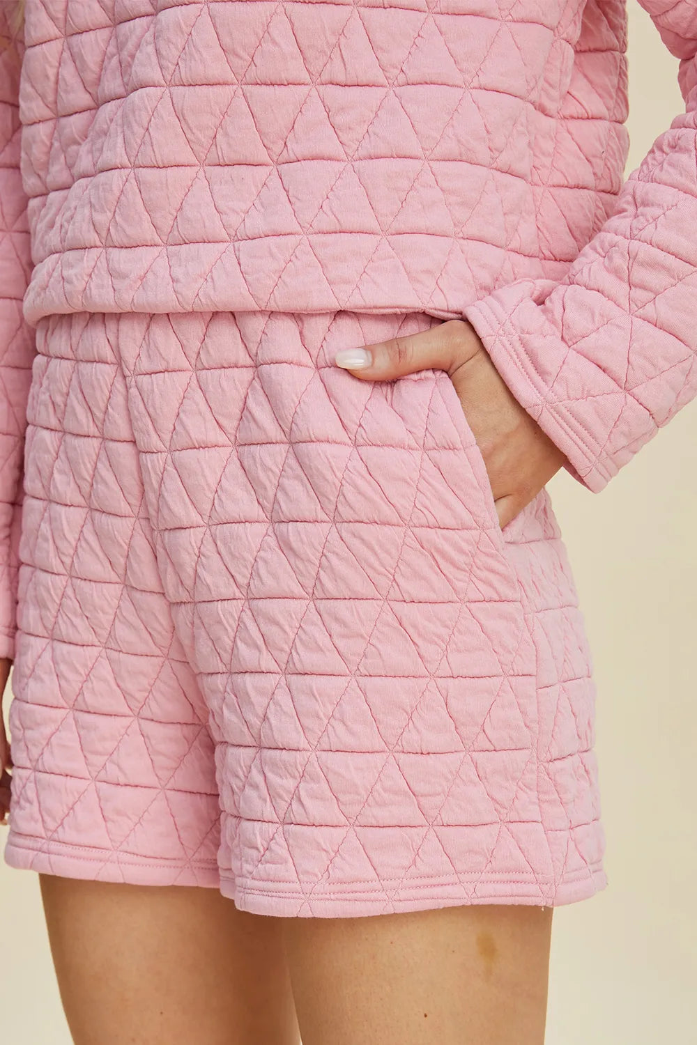 Pink quilted shorts with geometric triangle texture and stitched pocket seam detail.