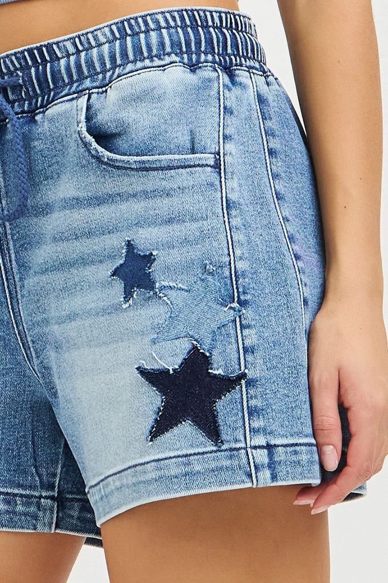 Side close-up of denim slouchy shorts: star patch on leg and patch pocket