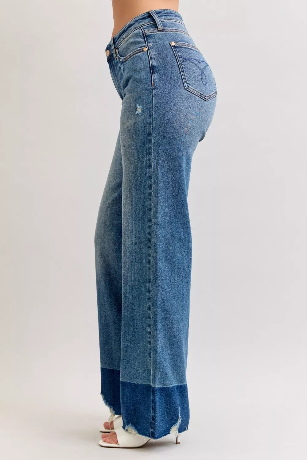 Rear three-quarter view of high-waist straight jeans in dark denim with raw frayed hem