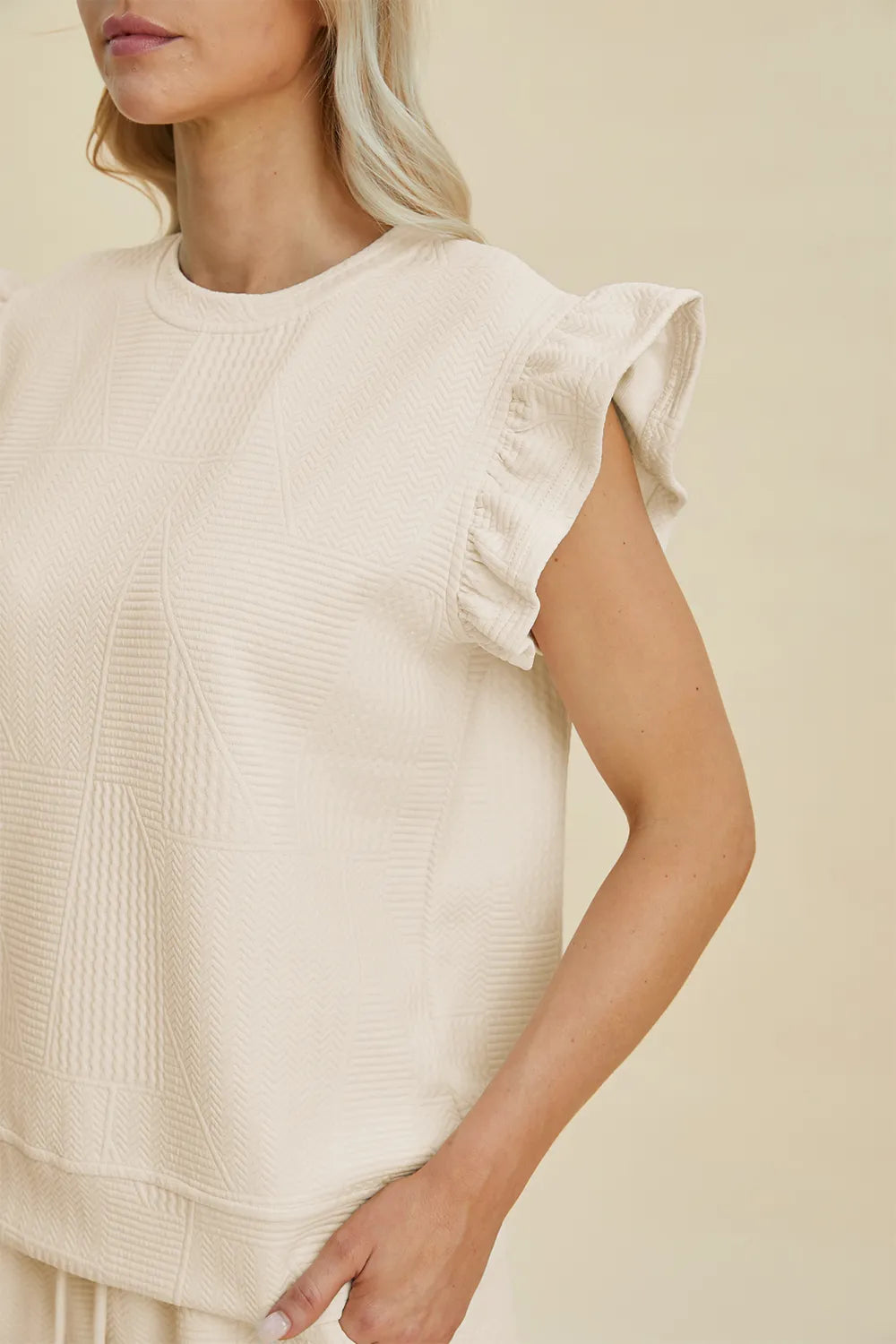 Cream textured top with round neck and ruffle sleeves, paired with shorts set