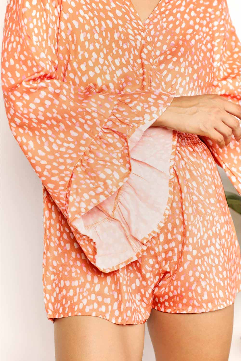 Close-up: tangerine printed surplice romper with V neckline and cinched waist