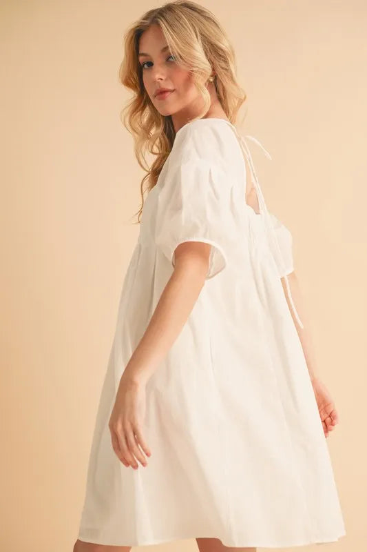 White square-neck babydoll dress, side view of puff sleeves and flared skirt