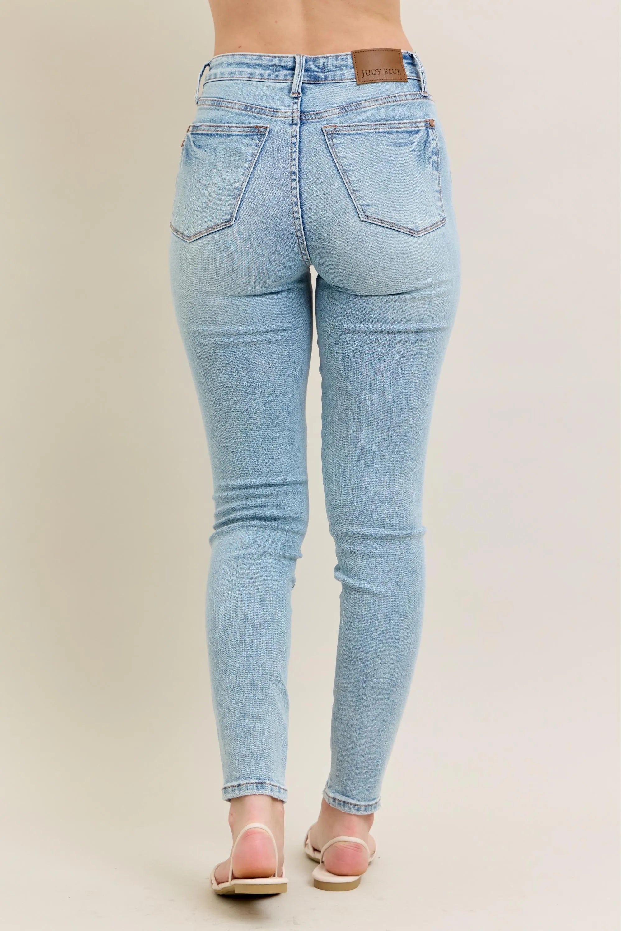 Light wash skinny jeans, back view with stitched back pockets and logo patch at waist