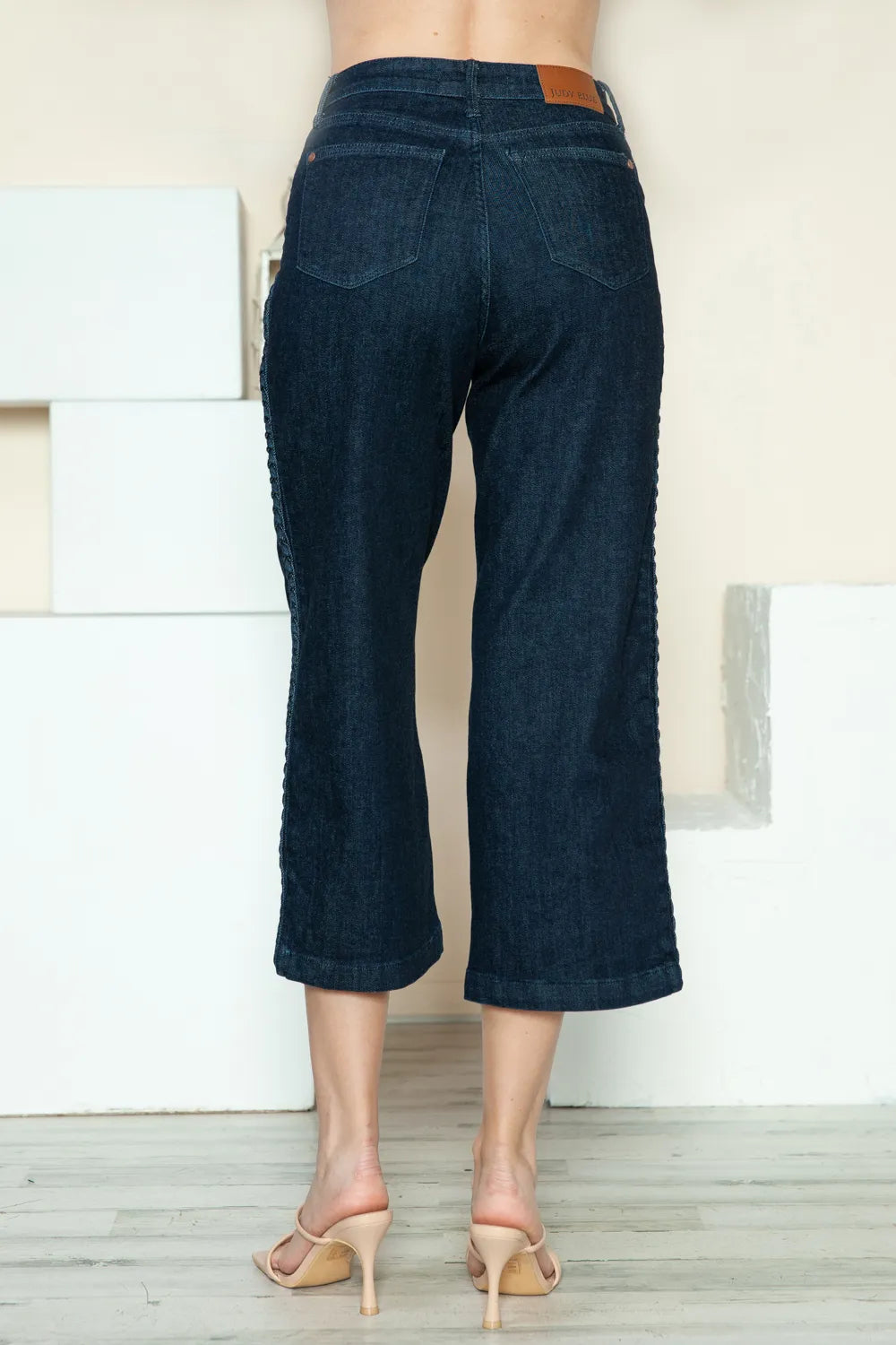 Dark wide-leg crop jeans from back view with stitched seams and cropped leg opening