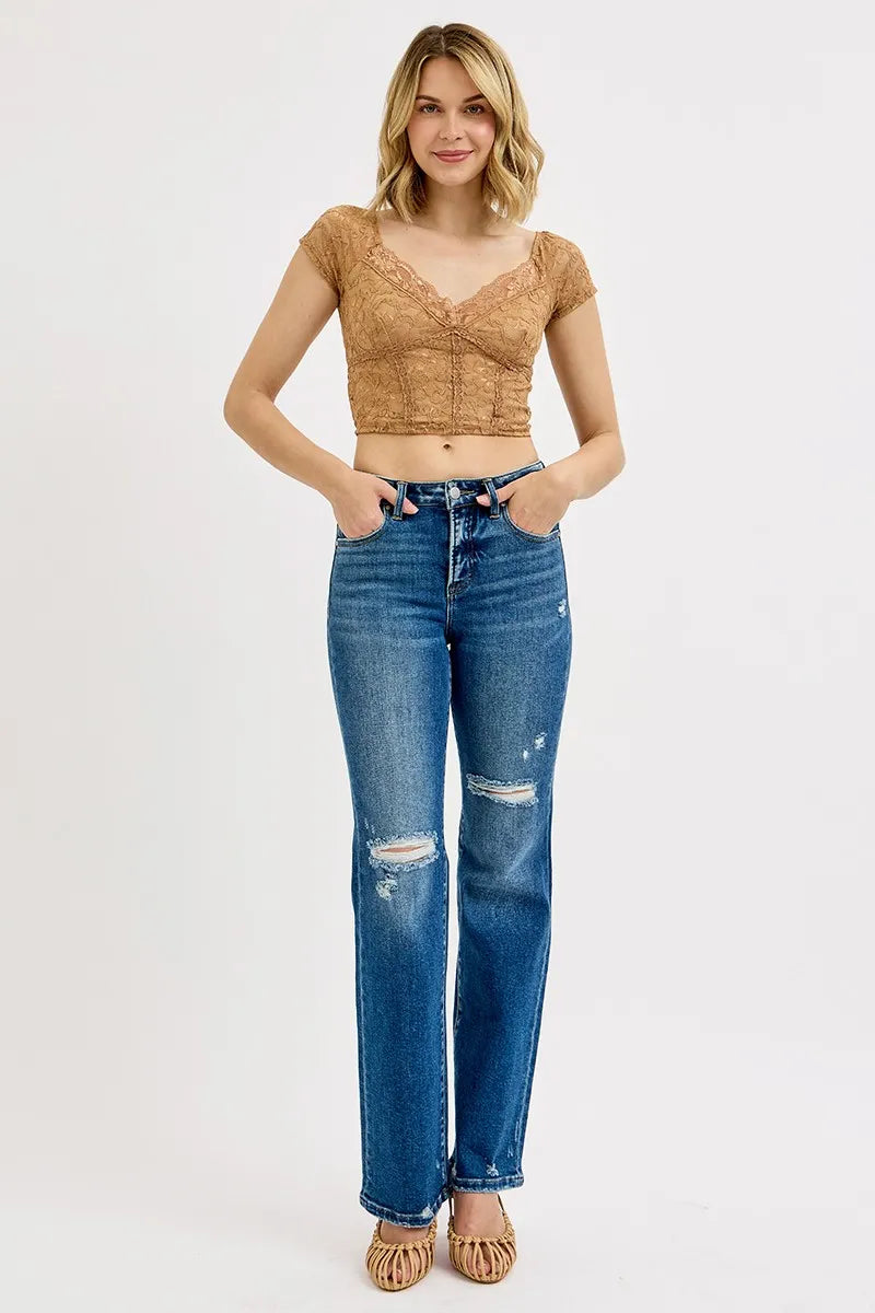 Dark high-rise straight distressed jeans on model, frayed knee rips and ankle hem