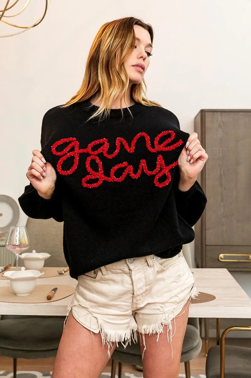 Black sweater with red “Game Day” script across chest, crew neck and shoulders