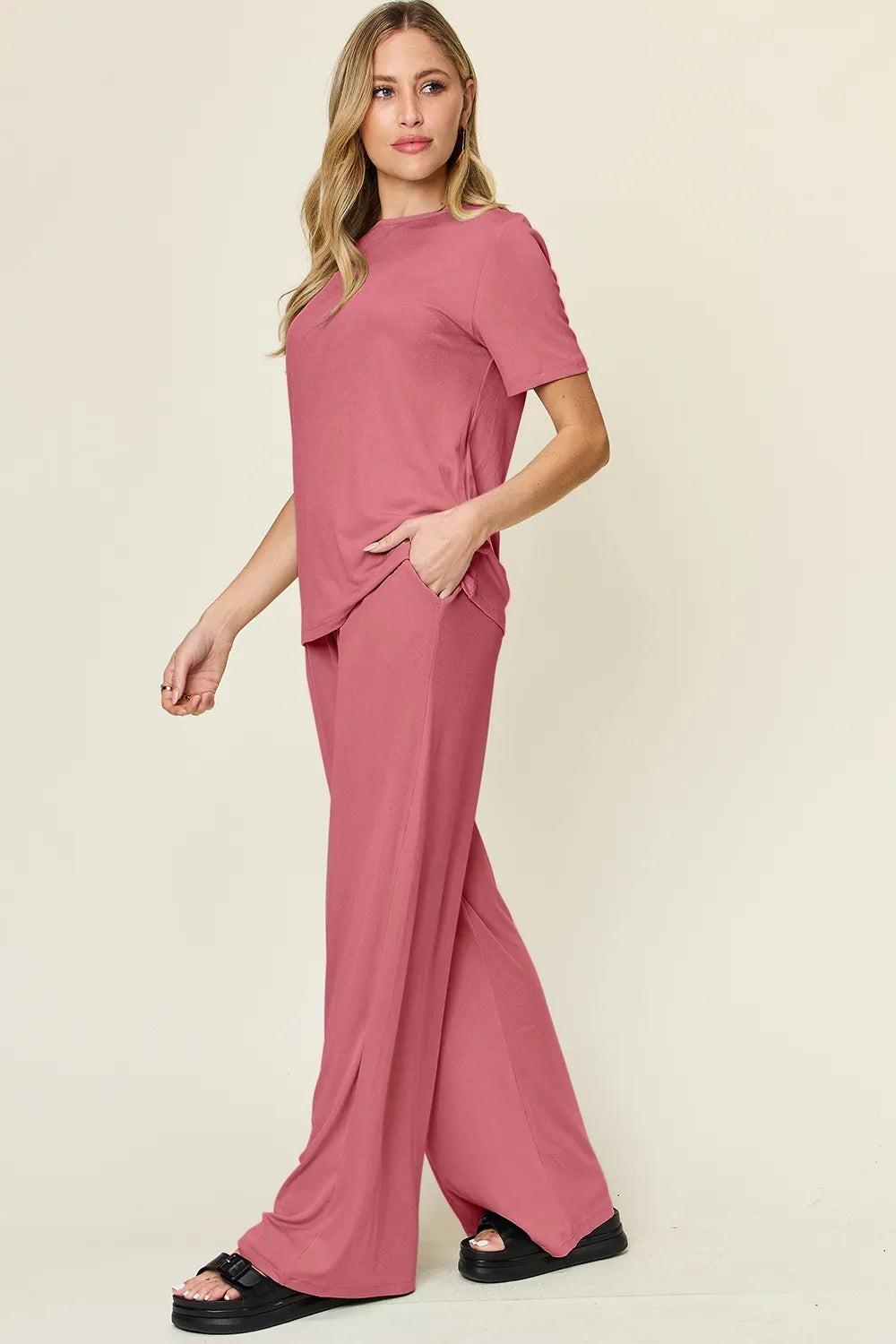 Pink round-neck T-shirt with wide-leg pants, draped front hem