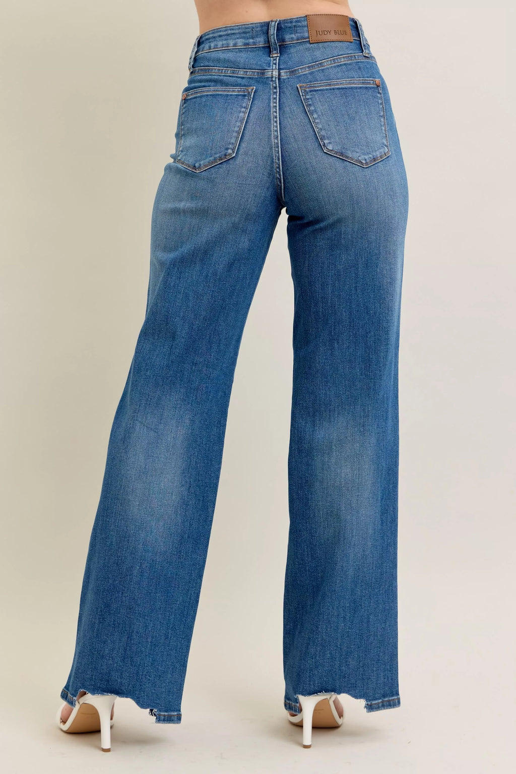 Medium-wash wide-leg jeans from behind with belt loops and raw frayed hem