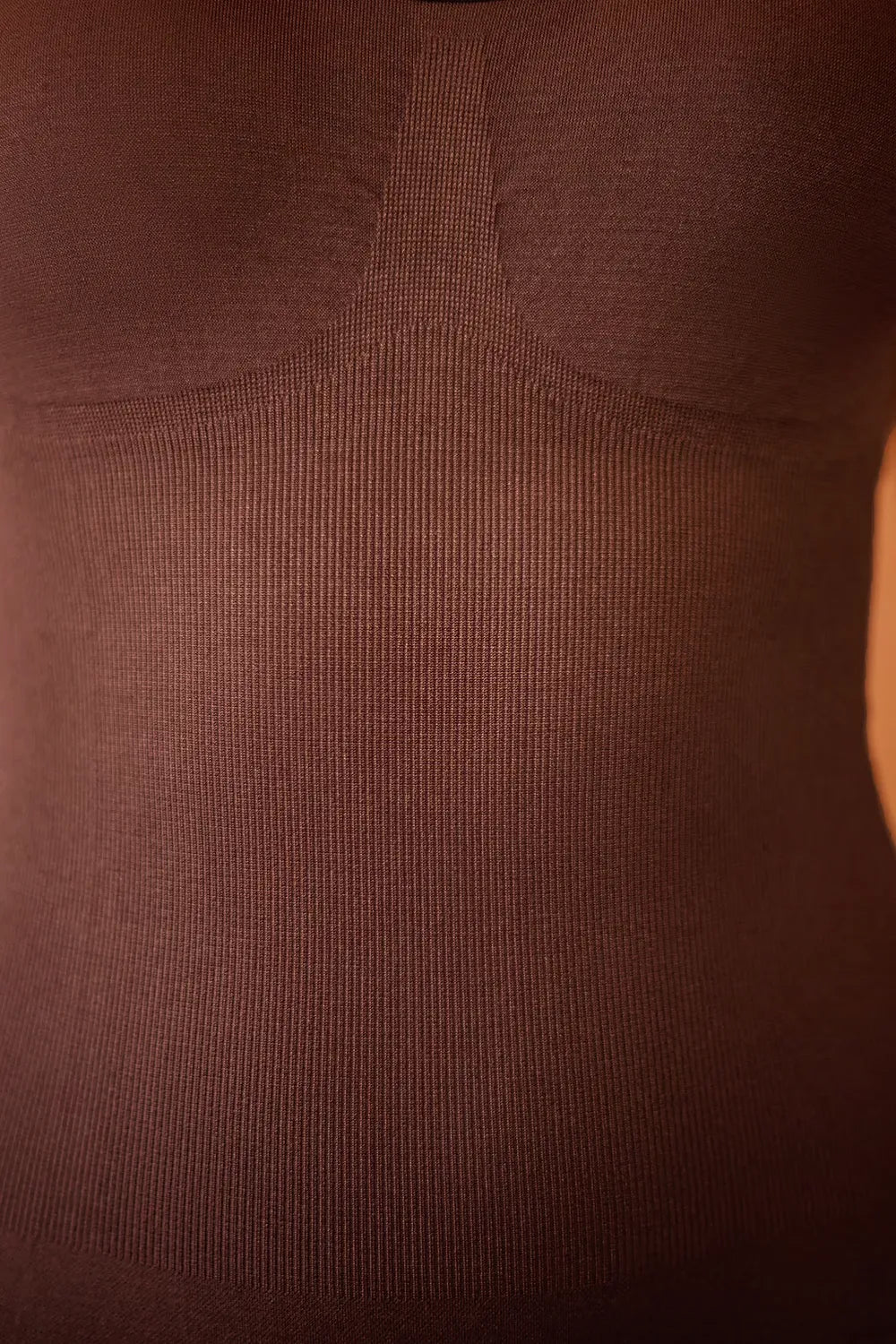 Brown bodysuit fabric close-up with ribbed stretch texture