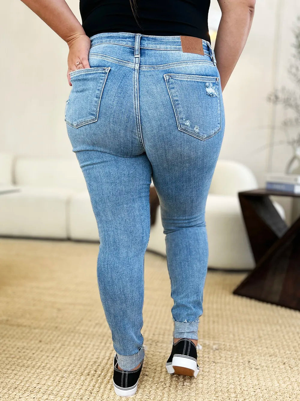 Back view: medium wash mid rise skinny jeans with back pocket distress and cuff hem