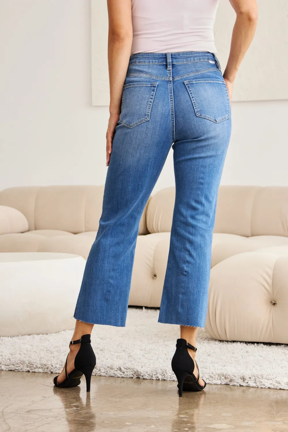 Back view: medium wash high-waist tummy-control jeans with cropped flared legs